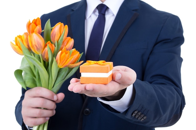 Gift box with wedding ring and flowers in male hands isolated on white background