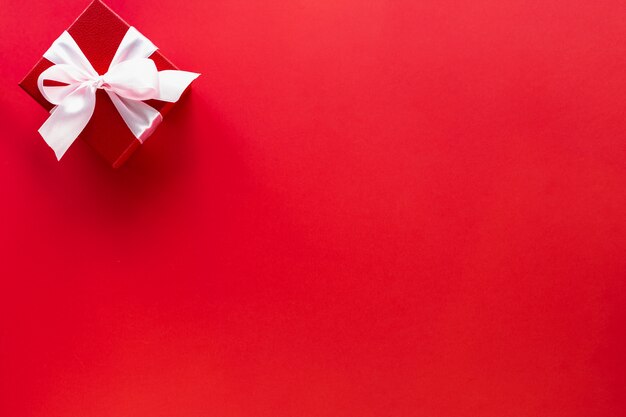 Подарочная коробка с белым бантом на красном, вид сверху с копией пространства