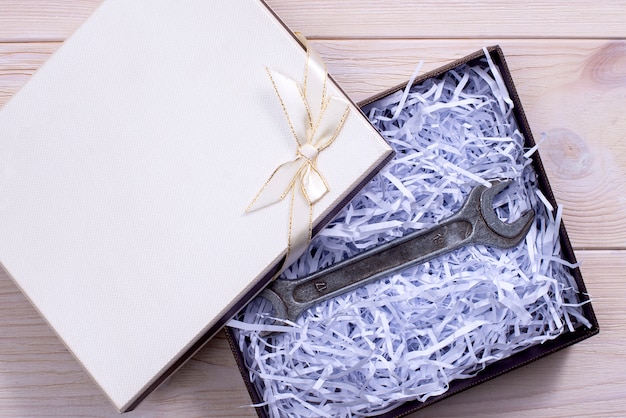 Photo gift box on wooden light background. wrench.