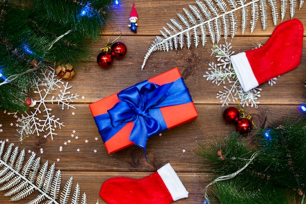 Gift box on a wooden table, table with pine branches and red balls