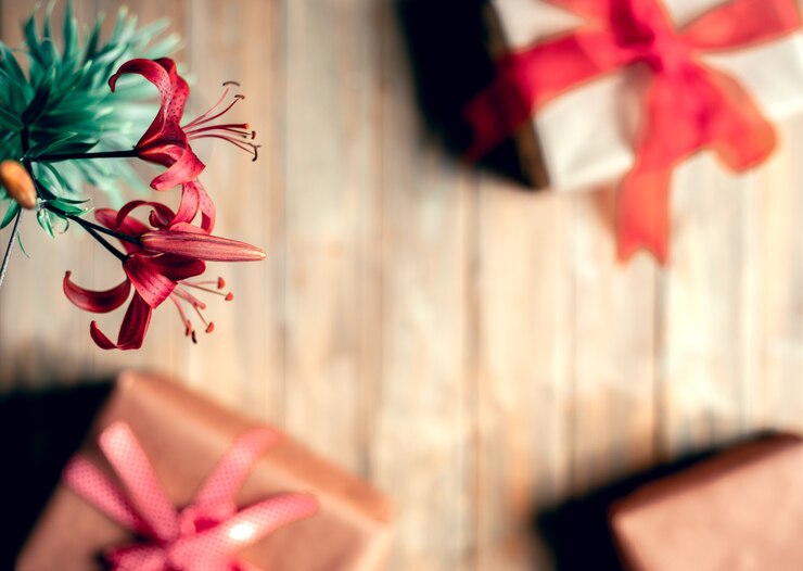 Photo gift box wrapped in kraft paper and a red lily flower on a wooden table.