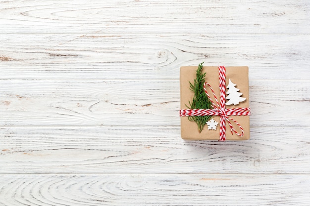 Gift box wrapped in recycled paper, with ribbon bow, with christmas decor. Wooden table background, copyspace