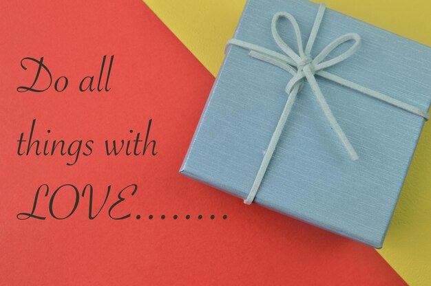 Gift box on yellow and red background with text DO ALL THINGS WITH LOVE