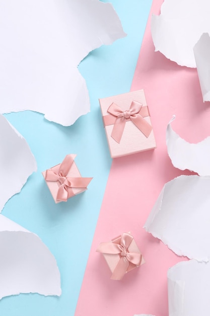 Gift boxes on bluepink background with torn paper Concept art Pastel color trend Top view