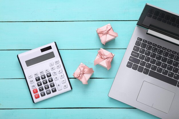 Gift boxes calculator and laptop on blue wooden background Top view