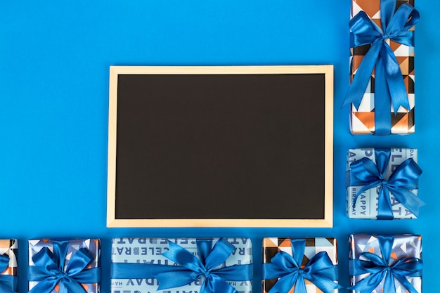 Photo gift boxes and chalkboard on blue background with copy space.