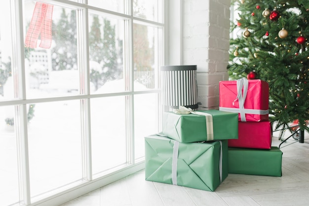 아늑한 집 창문 근처의 크리스마스 트리 아래 선물 상자