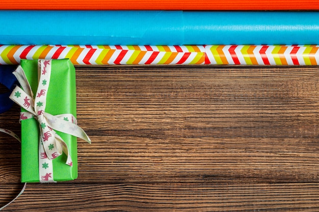 Gift boxes and colorful wrapping paper on a wooden brown background