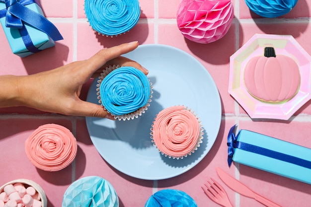 Gift boxes cupcakes and female hand on pink background top view