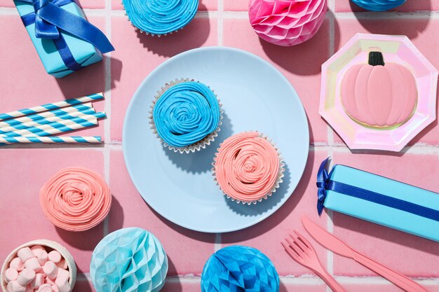 Gift boxes and cupcakes on plates on pink background top view