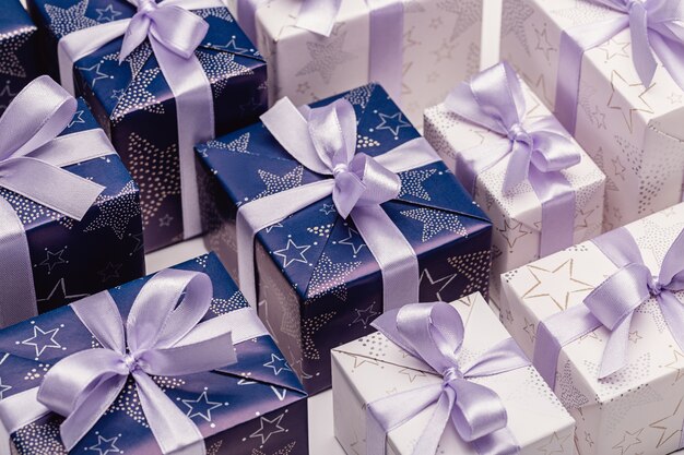 Gift boxes in elegant paper with lilac ribbons. Happy Holidays.