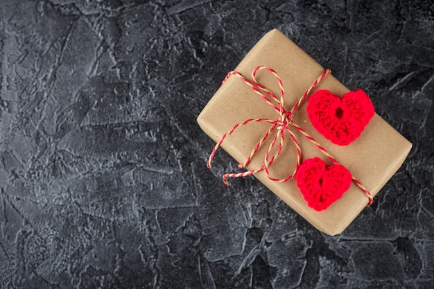 Подарочные коробки из крафт-бумаги и декоративные сердечки, связанные крючком. День святого Валентина Вид сверху.
