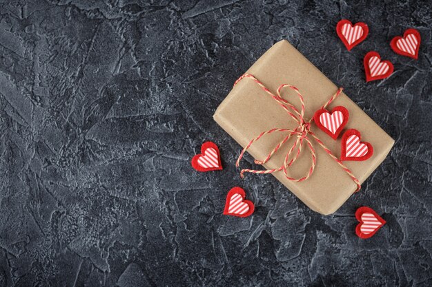 Gift boxes in kraft paper, decorative ribbon with wooden hearts and decorative felt hearts. Valentine's Day. Flat lay. Top view.