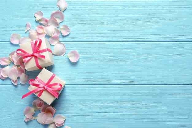 Gift boxes and petals on wooden background