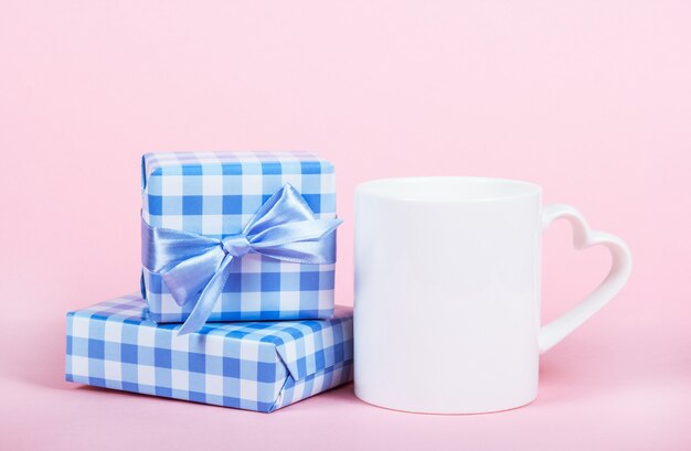 Gift boxes and white cup on pink background