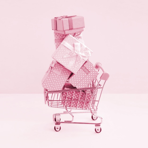 Gift boxes for winter holidays in supermarket shopping cart Image toned in Viva Magenta color of the 2023 year