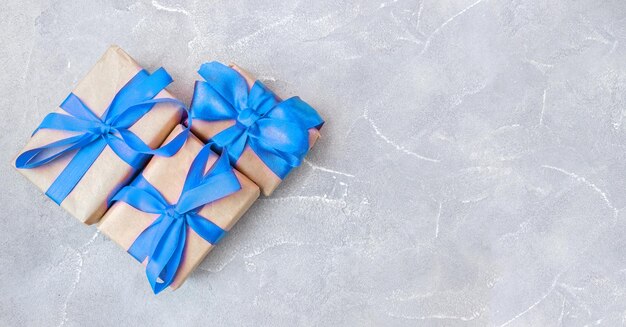 Gift boxes with a blue bow on concrete background. Banner. Copy space. Flat lay. Top view. The concept of any holiday