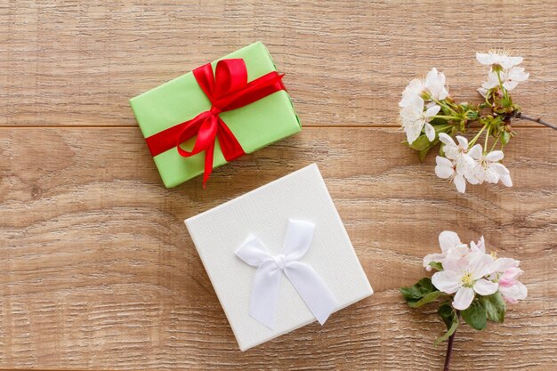 Gift boxes with cherry flowers on the wooden background