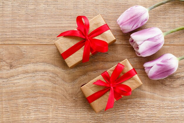 Gift boxes with lilac tulips on wooden boards Greeting card concept Top view