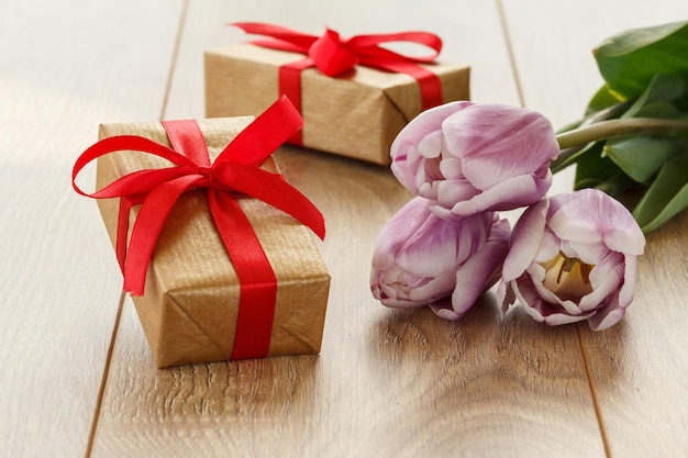 Gift boxes with lilac tulips on the wooden boards. Greeting card concept.