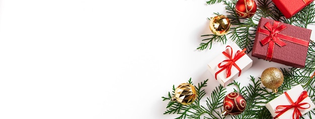 Gift boxes with red ribbon and golden Christmas balls on a white background.