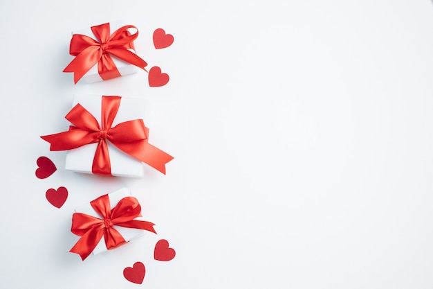 Gift boxes with red ribbon and hearts on white