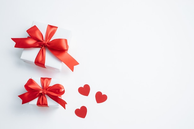 Gift boxes with red ribbon and hearts on white