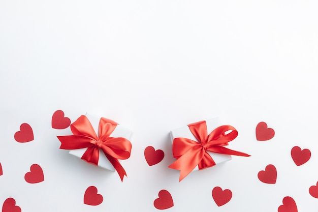 Gift boxes with red ribbon and hearts on white