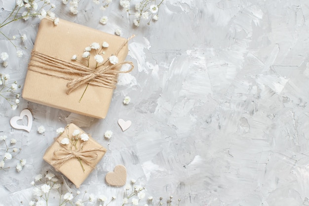 Gift boxes with small white flowers and hearts on a grey background