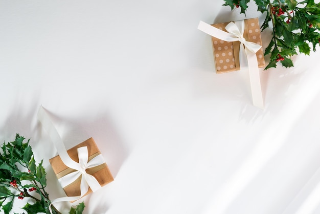 Gift boxes with snow holly branches and sunlight rays . Christmas card. Flat lay copyspace