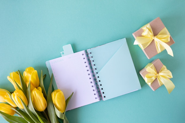 Gift boxes, yellow tulips and a notebook