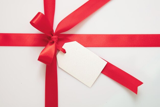 Gift card blank and red ribbon bow on white background Christmas valentine present concept