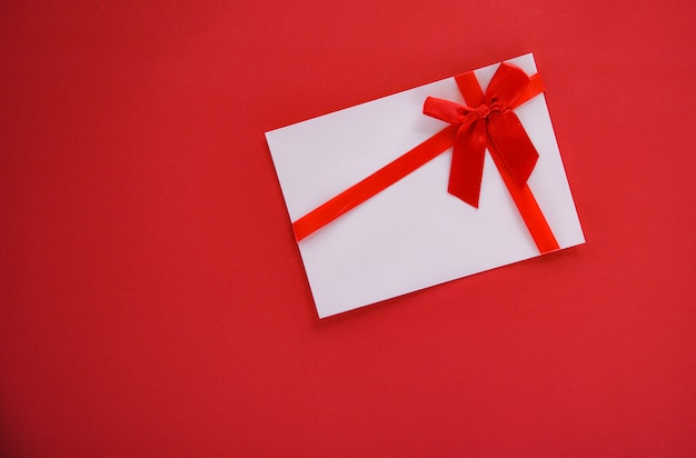 Gift card on red background with red ribbon bow Gift voucher on red background top view copy space