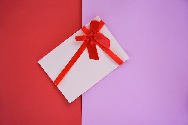 Gift card on red and pink background Gift card decorated with red ribbon bow