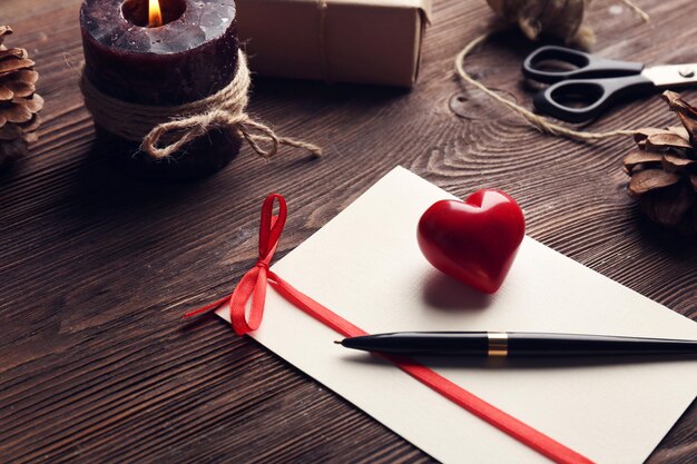 Gift card for Valentine's Day with pen and candle on wooden background