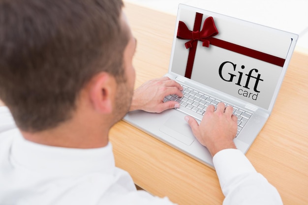 Gift card with festive bow against businessman working at his desk