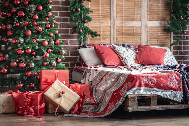 寝室のクリスマスツリーの近く、クリスマススタイルの居心地の良い部屋のインテリアにクリスマスプレゼントを贈りましょう。