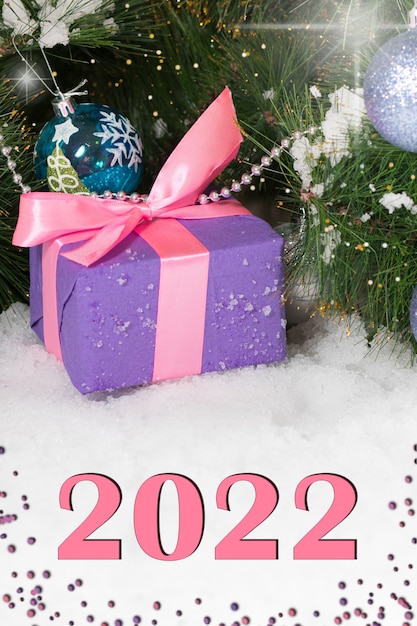 A gift for Christmas in the snow under the tree with with number 2022