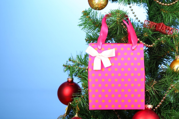 Gift on Christmas tree on color background