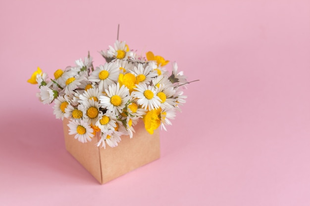 Gift craft box with daisies flowers on pink