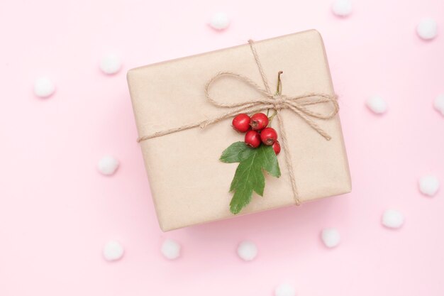 Photo gift in craft packaging and with natural decor on a pink background, christmas concept, top view.