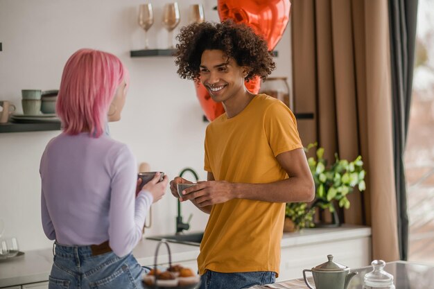 A gift Curlyhaired young man congratulating his girlfriend with valentines day