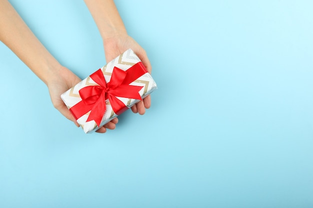 Gift in female hands on a colored background top view