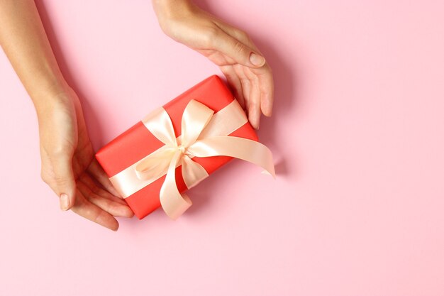 Gift in female hands on a colored background top view