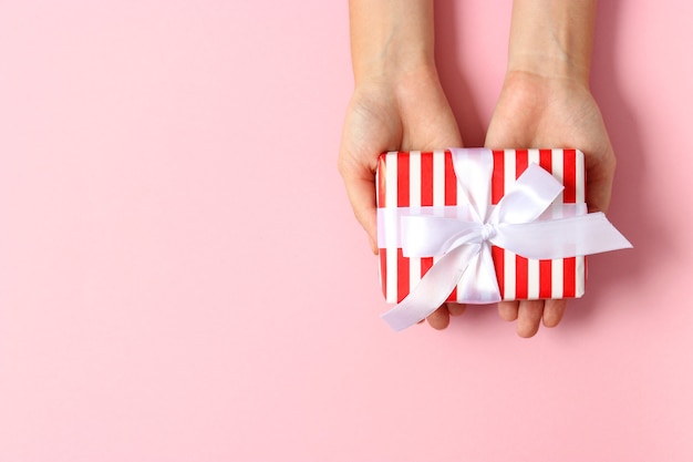 Gift in female hands on a colored background top view