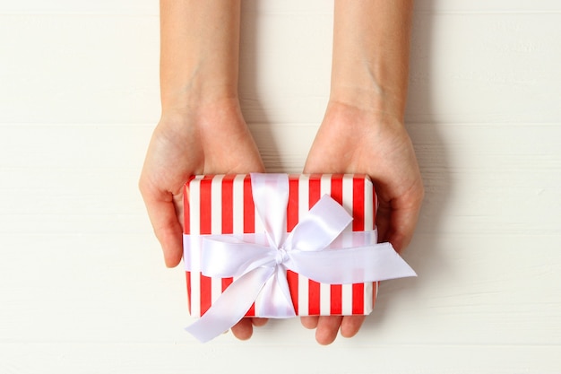 Gift in female hands on a colored background top view