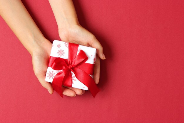 Gift in female hands on a colored background top view