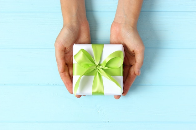 Gift in female hands on a colored background top view