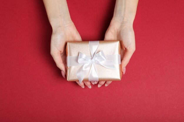 Gift in female hands on a colored background top view