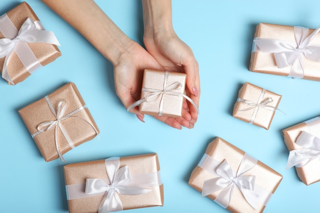 Gift in female hands on a colored background top view